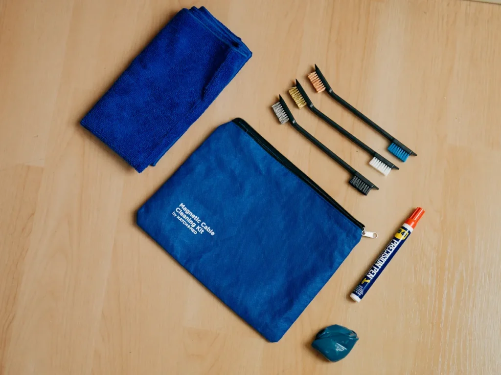 The BlackJack maintenance kit laid out on a table: a blue pouch, a microfiber cloth, three brushes, a WD-40 precision pen and a tin of blue magnetic putty.