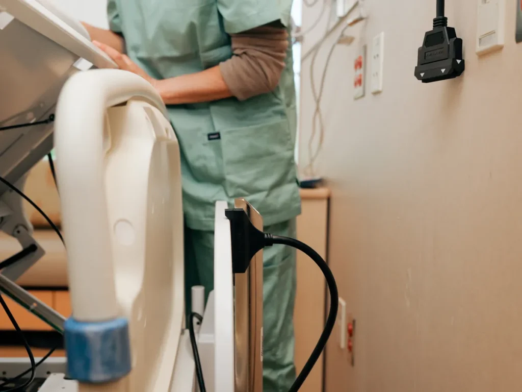 A nurse at a hospital bed with a BlackJack cable plugged into the bed and its wall end on the headwall behind.