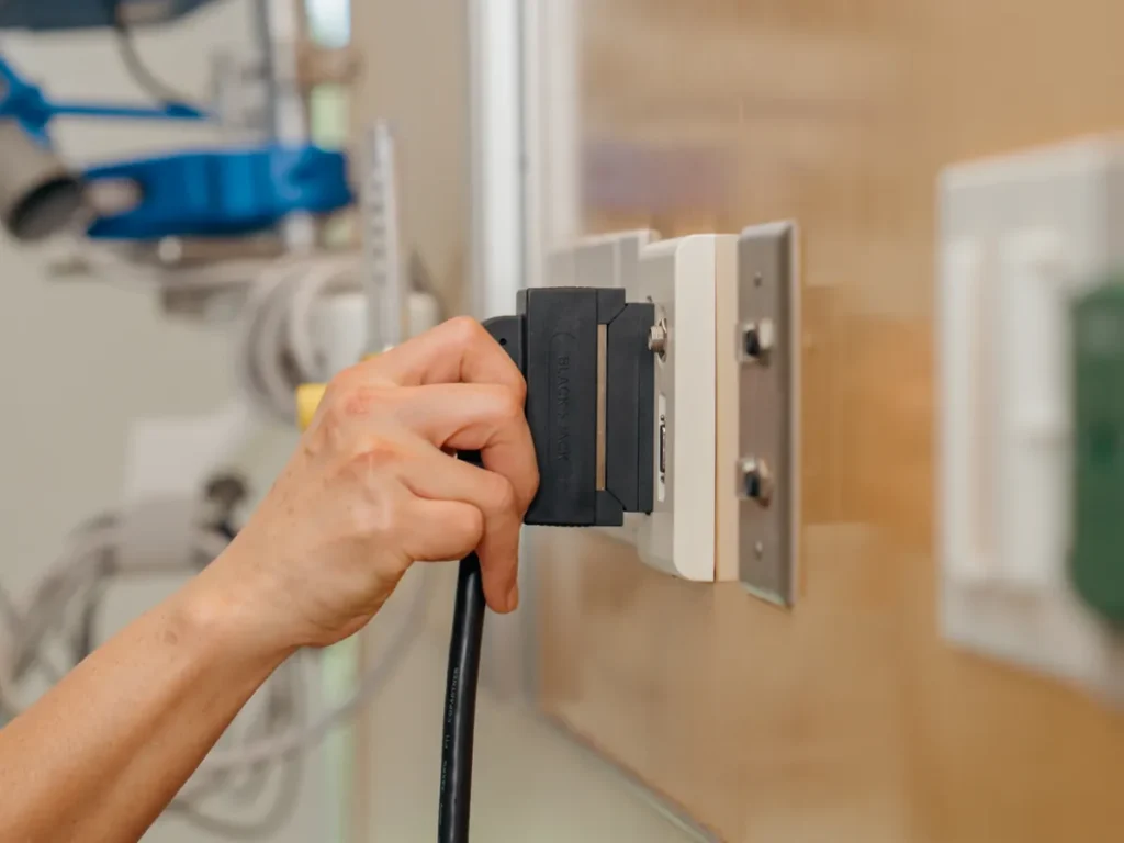 A hand places a BlackJack cable connector against its mating half on the wall.