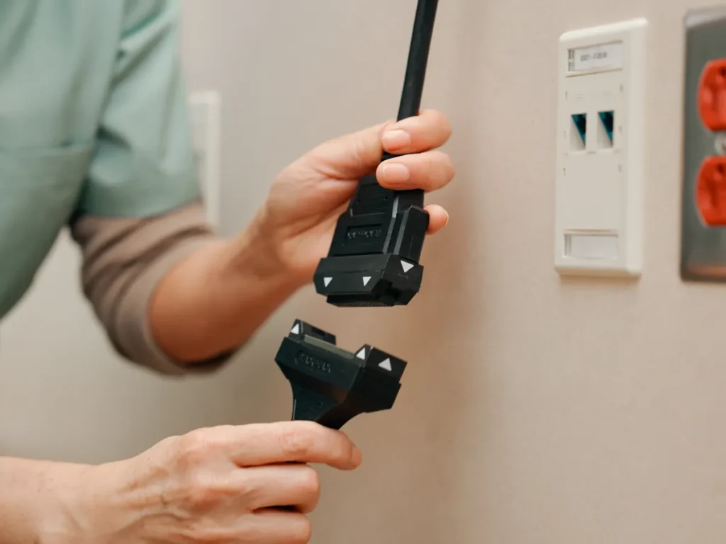 A nurse pulls the two magnetic halves of a BlackJack cable apart in front of a headwall.