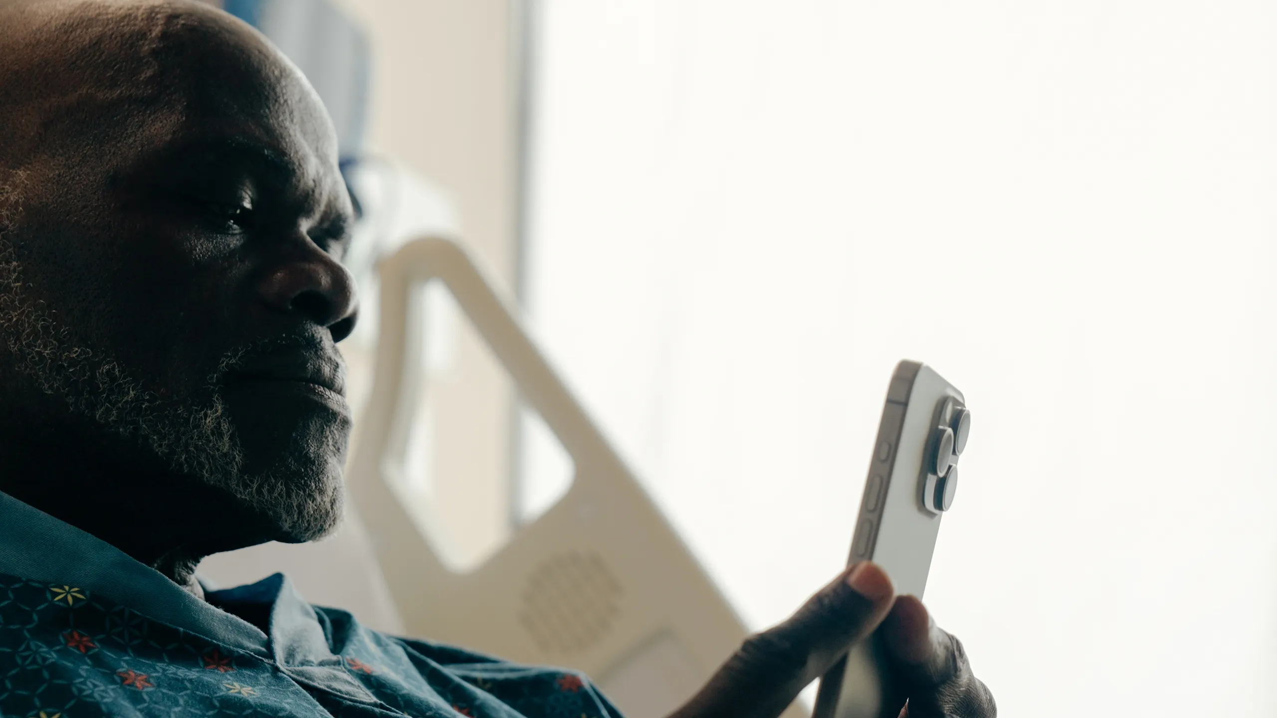 Patient silhouette with a phone against a hospital window