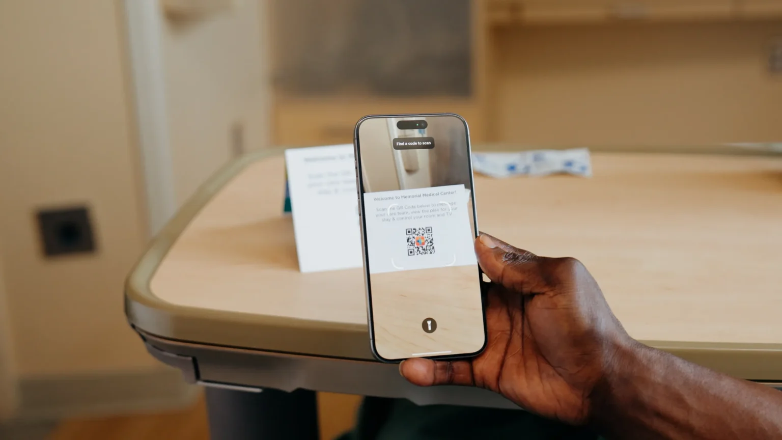 Patient scanning the room QR code with a phone at the bedside table