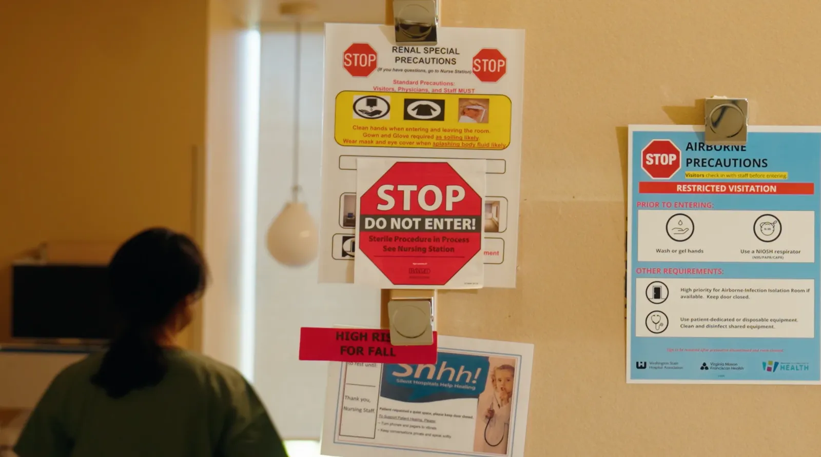 Hospital room door covered in paper precaution and isolation signs