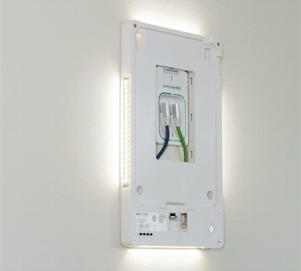 The back panel of a HallMonitor mounted over its PoE+ splitter, with the light panels glowing white.