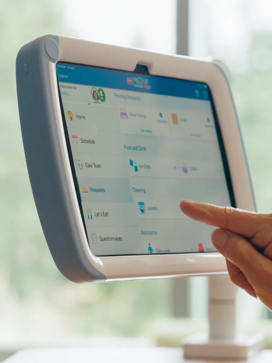 A finger taps the Epic MyChart Bedside app on a PillowCase mounted on an arm.