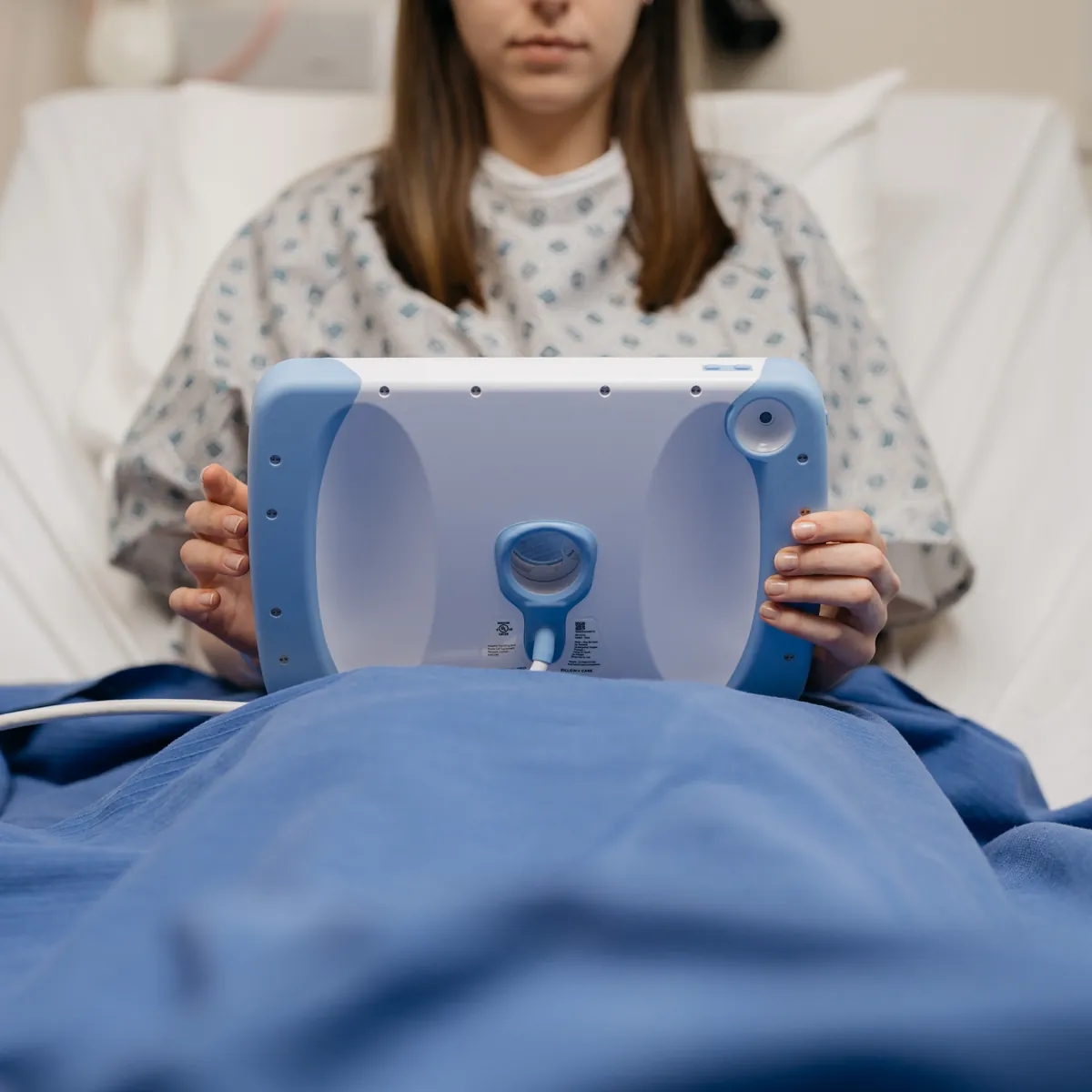 The back of a PillowCase held by a patient, with its camera opening and the magnetic cable at the bottom.