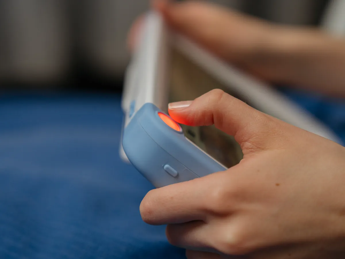 A finger presses the lit orange call button on the corner of a PillowCase.