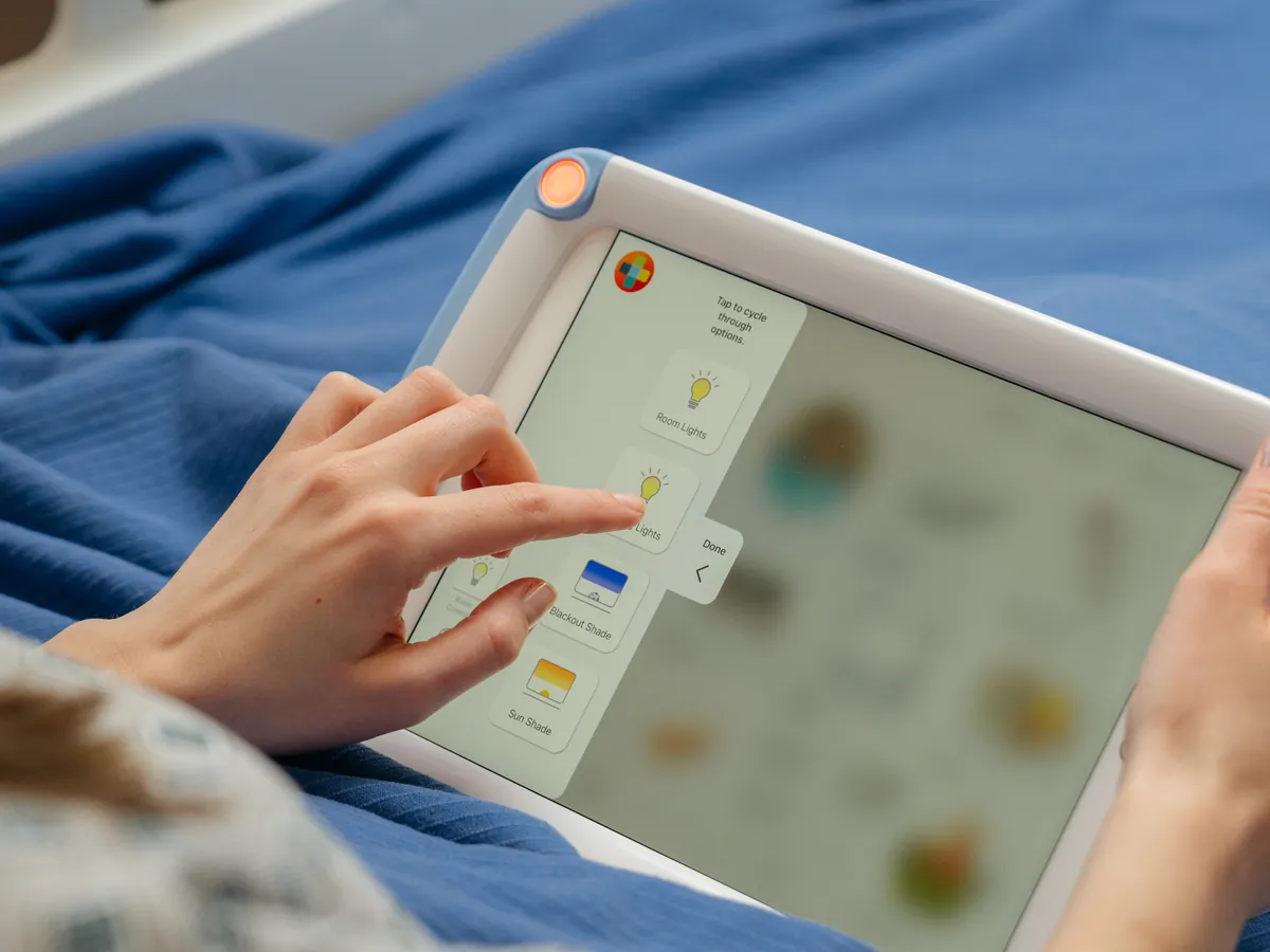 A patient taps a reading light control in the ComCierge app on a PillowCase.